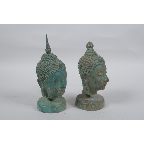 298 - A pair of bronze Buddha's heads with green patina, mounted on a metal stand, 16.5cm high