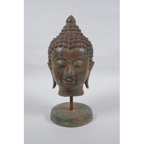 300 - A bronze Buddha head bust on a metal base, with green patina, 25cm high