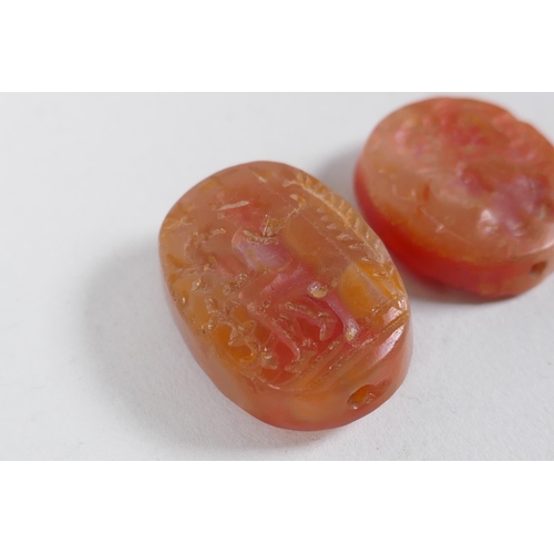 308 - Two Persian amber agate intaglio beads with figural decoration, 2 x 2.5cm