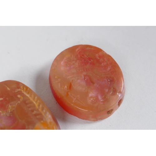 308 - Two Persian amber agate intaglio beads with figural decoration, 2 x 2.5cm