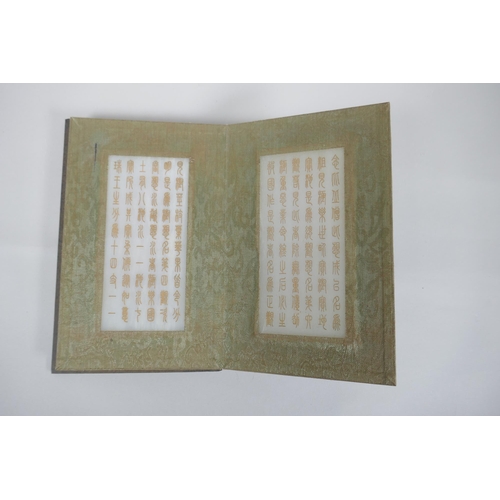 40 - A Chinese wood and silk bound book containing white jade tablet pages with chased and gilt inscripti... 