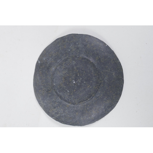 43 - A Persian carved stone dish depicting a lion slayer, 15cm diameter