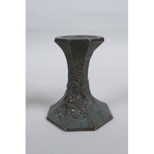 54 - A pair of early C20th Japanese bronze candlesticks of hexagonal waisted form, with raised floral dec... 