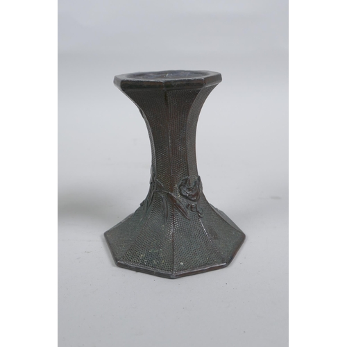 54 - A pair of early C20th Japanese bronze candlesticks of hexagonal waisted form, with raised floral dec... 