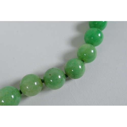 611 - An apple green jade bead necklace, 82cm long