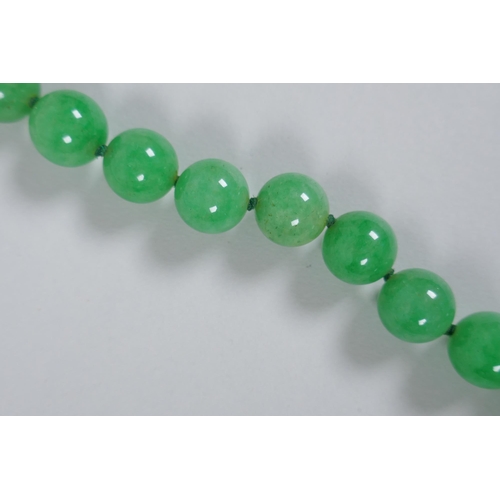 611 - An apple green jade bead necklace, 82cm long