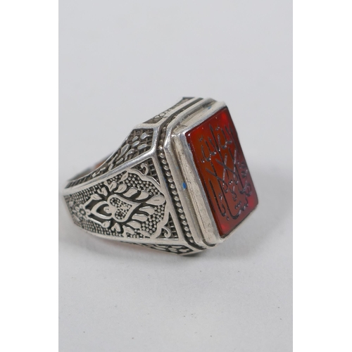 633 - An Islamic white metal ring set with an amber agate intaglio seal, size S/T