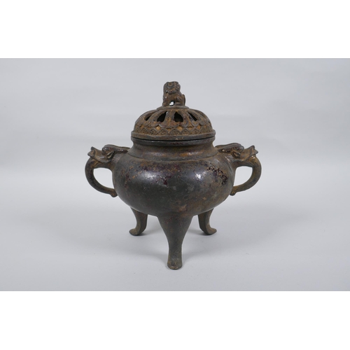 74 - A Chinese gilt bronze censer and pierced cover, raised on tripod supports, with two dragon mask hand... 