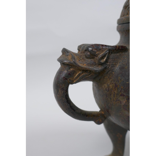 74 - A Chinese gilt bronze censer and pierced cover, raised on tripod supports, with two dragon mask hand... 