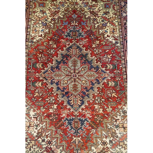 1174 - An antique Persian red and cream ground Heriz full pile carpet with black borders, 210 x 296cm