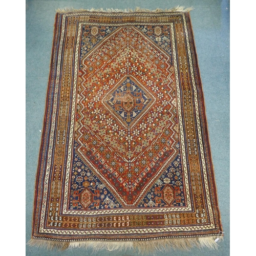 1127 - A Persian red ground wool Ghashghai carpet with unique medallion design, 172 x 260cm