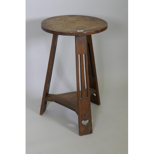 1004 - An Arts & Crafts oak occasional table, the circular top raised on three pierced splay supports u... 