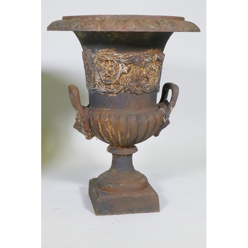 1015 - A pair of cast iron garden urns with two mask handles and raised decorative frieze, 60cm high