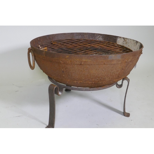 1051 - A cast iron fire pit on tripod stand, 61cm diameter