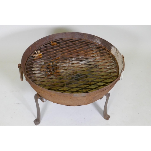 1051 - A cast iron fire pit on tripod stand, 61cm diameter