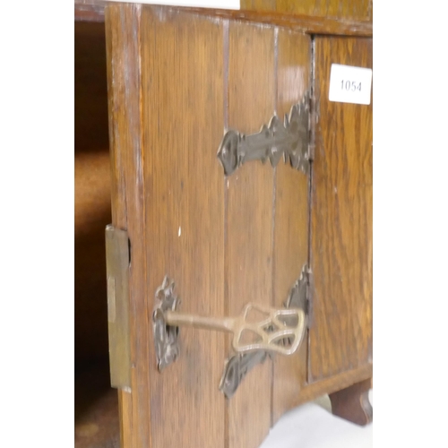 1054 - An Arts and Crafts oak cabinet with pierced decoration and metal mounts, 38 x 17 x 55cm