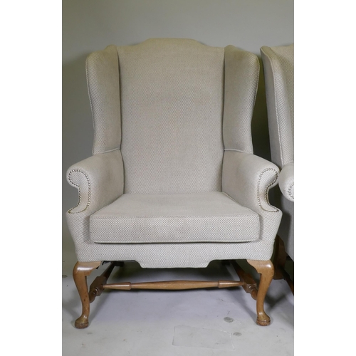 1057 - A good pair of Georgian style high back wing armchairs with wide seats, raised on walnut cabriole su... 