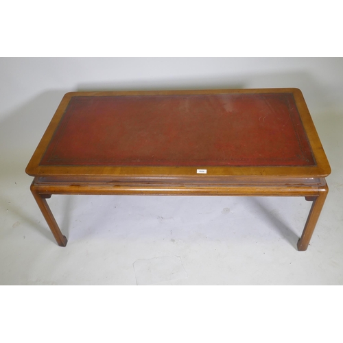 1058 - A Chinese style walnut coffee table with inset tooled leather top, 126 x 65 x 52cm