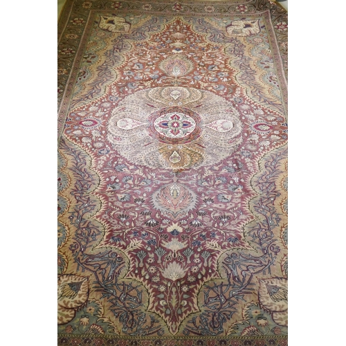 1060 - A Turkish Hereke wool carpet with central design on a faded terracotta field, with blue/grey borders... 