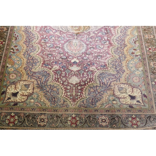 1060 - A Turkish Hereke wool carpet with central design on a faded terracotta field, with blue/grey borders... 