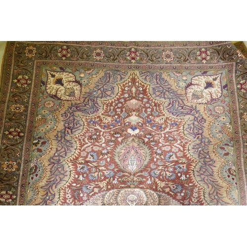 1060 - A Turkish Hereke wool carpet with central design on a faded terracotta field, with blue/grey borders... 