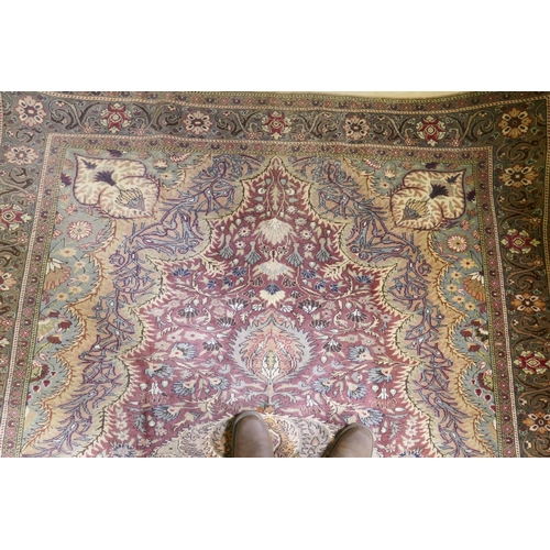 1060 - A Turkish Hereke wool carpet with central design on a faded terracotta field, with blue/grey borders... 