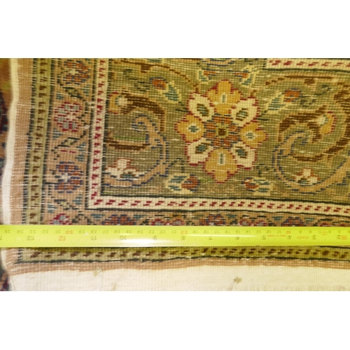 1060 - A Turkish Hereke wool carpet with central design on a faded terracotta field, with blue/grey borders... 