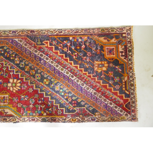 1065 - A Kashkai wool runner with geometric designs on a red field, 84 x 174