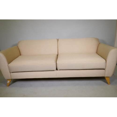 1079 - A contemporary design two seater sofa with linen covers, raised on splay supports, 188cm wide