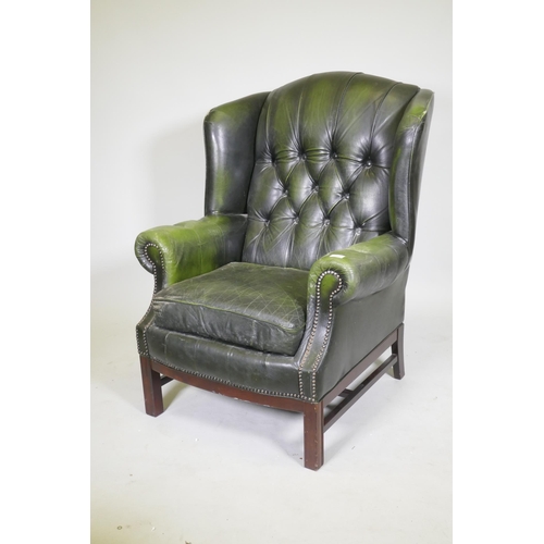 1082 - A Georgian style button back leather wing armchair with brass stud decoration