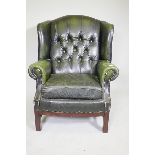 1082 - A Georgian style button back leather wing armchair with brass stud decoration