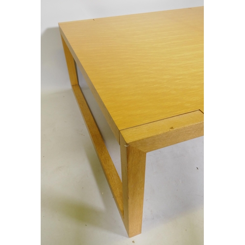 1095 - A contemporary blond oak coffee table, raised on square end supports, 120 x 120 x 48cm