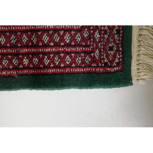 1103 - A Persian red ground wool runner with Bokhara style design and emerald green borders, 64 x 188cm