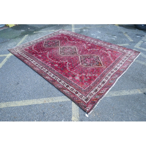 1116 - A Persian washed red ground full pile Qashqai tribal carpet, 216 x 294cm