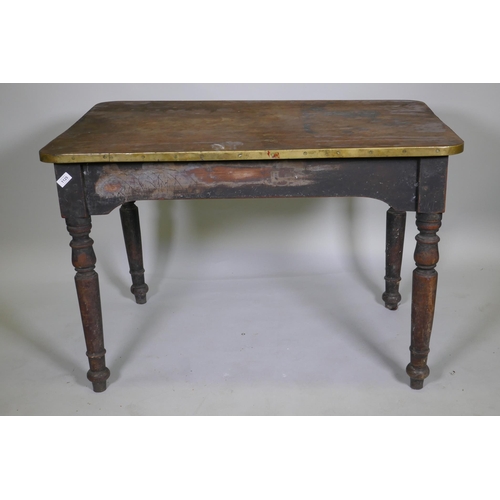 1125 - A C19th mahogany tavern type table, the one piece top with brass edge, raised on turned supports, 10... 