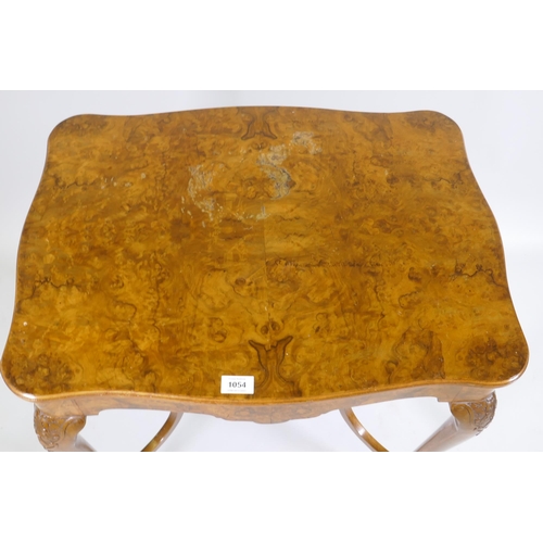 1128 - A burr walnut centre table, with shaped top and pull out slides, raised on carved cabriole supports ... 