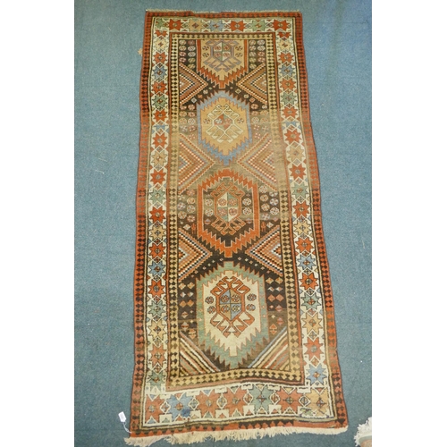 1129 - A multi colour ground Kurdish Kazak wool runner with a geometric medallion design on a brown field, ... 