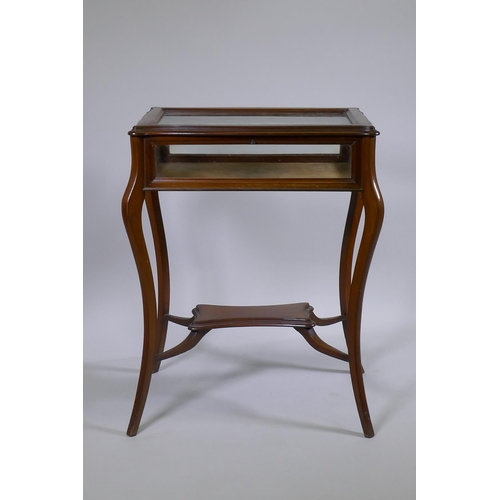 1153 - A mahogany bijouterie cabinet with shaped top, raised on splay supports united by an under tier, 65 ... 