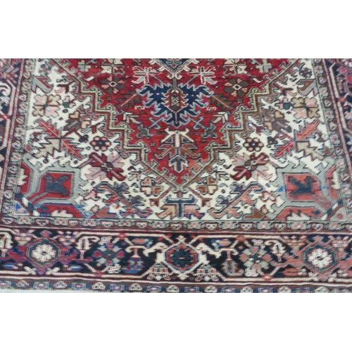 1174 - An antique Persian red and cream ground Heriz full pile carpet with black borders, 210 x 296cm