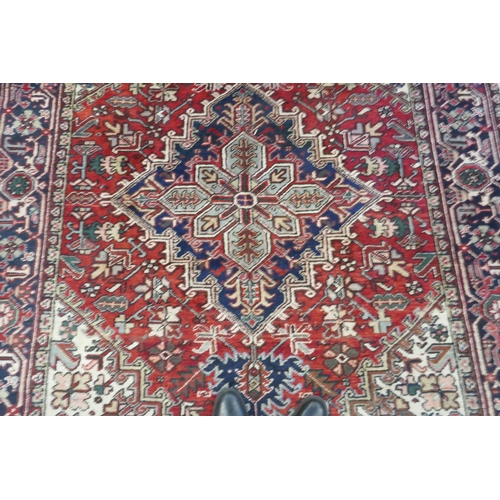 1174 - An antique Persian red and cream ground Heriz full pile carpet with black borders, 210 x 296cm