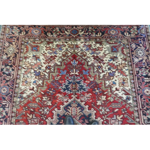 1174 - An antique Persian red and cream ground Heriz full pile carpet with black borders, 210 x 296cm