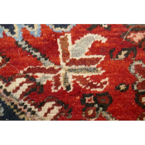 1174 - An antique Persian red and cream ground Heriz full pile carpet with black borders, 210 x 296cm