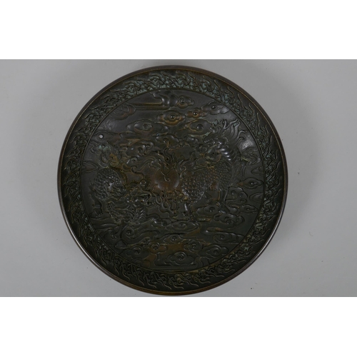 125 - A Chinese bronze dish with raised kylin decoration, Xuande 4 character mark to base, 18cm diameter