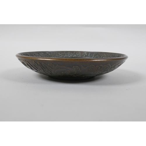 125 - A Chinese bronze dish with raised kylin decoration, Xuande 4 character mark to base, 18cm diameter