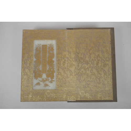 140 - A Chinese wood and silk bound book containing white jade tablet pages with chased and gilt inscripti... 