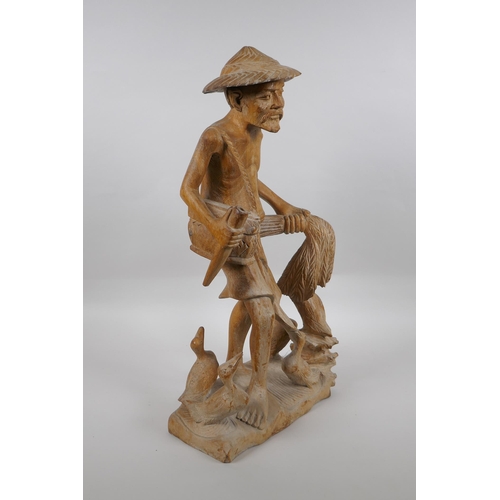 166 - An oriental carved wood figure of a farmer surrounded by ducks, 46cm high