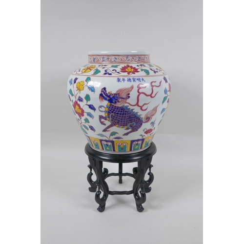 168 - A Chinese polychrome porcelain jar decorated with kylin and lotus flowers, on a carved hardwood stan... 