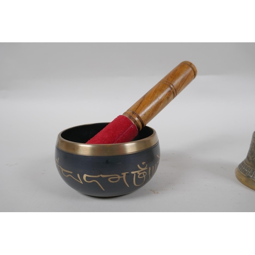 212 - A Tibetan bronze singing bowl and beater with script decoration, a brass ceremonial bell with silver... 