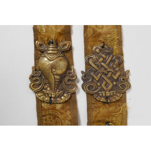 214 - A Tibetan silk sash mounted with brass emblems depicting the Buddhist treasures, 55cm long