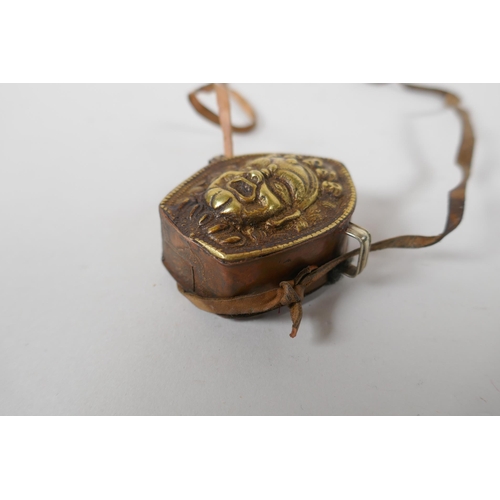 240 - A Tibetan copper and brass Gau box, with repousse wrathful deity mask decoration, 4 x 6cm